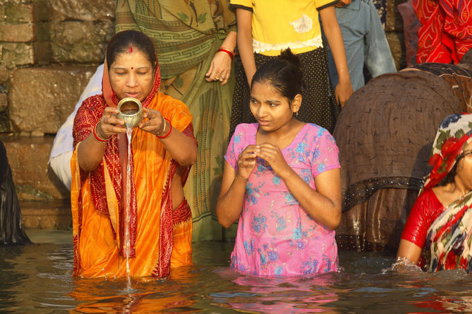Pilgrims bathing and pouring holy water at ghat on river Ganges.