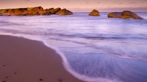 Red sandstone cliffs and seashore at sunset.