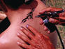 Young man getting spray-on tattoo in Lummus Park at South Beach.