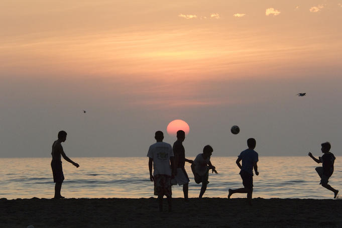 Boys playing beach soccer at sunset, Michoacan