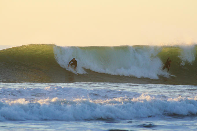 Surfers enjoy a wave at dusk near Okato.