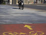 Person on bike and a yellow bicycle path mark on concrete.
