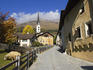 Tower of San Luzi church above old Engadine houses in the old town's center.