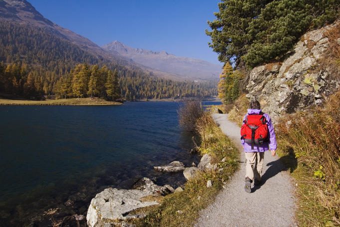 Hiker with a red pack walking on path along Champfersee (lake), Champfer.