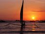 Paraw (traditional outrigger sailboat) sailing at sunset.