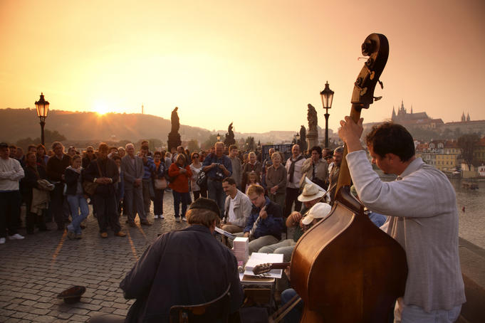 Tourists surround busker's near Charles bridge at sunset.