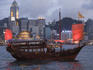 Traditional Chinese-style boat on Victoria Harbour with Hong Kong Convention and Exhibition Centre in background.