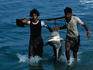 Two men bringing a shark to shore.
