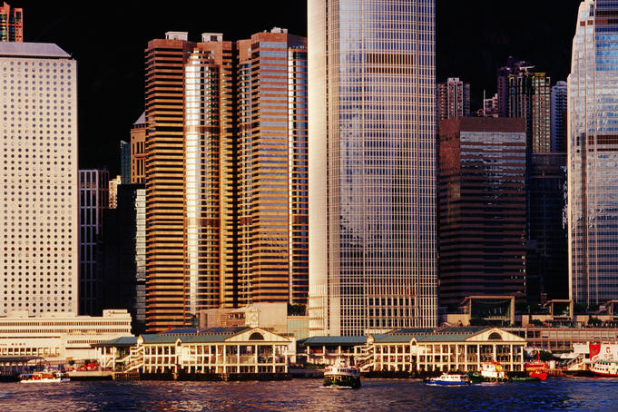Hong Kong Island buildings and Star Ferry Terminal on Victoria Harbour in Central at sunrise.