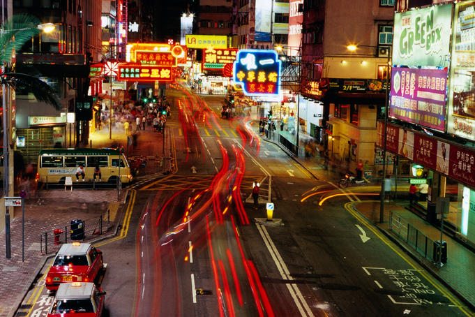 Traffic and neon signs in Causeway Bay at dusk.