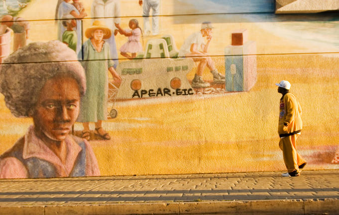 Man walks past a mural.
