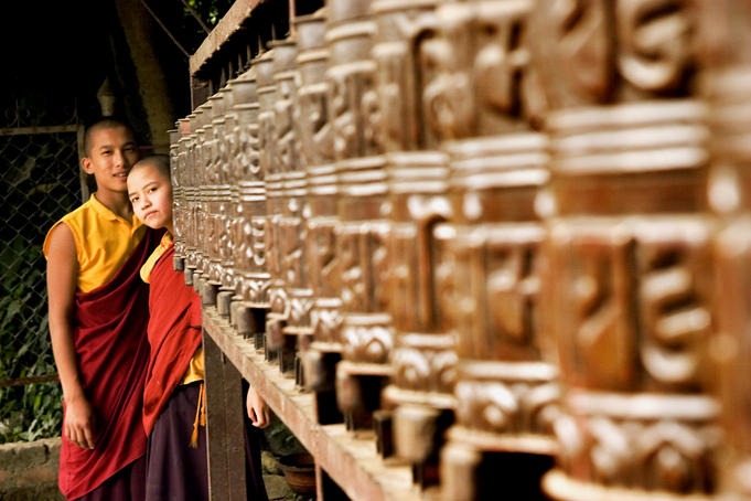 Two young monks behind prayer wheels.