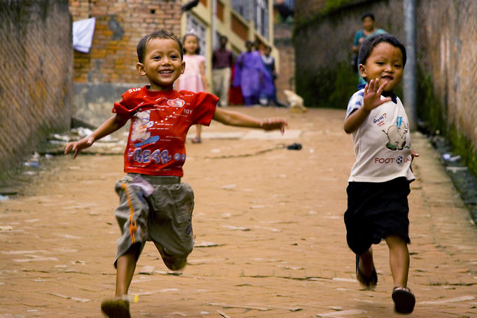 Two boys racing down dirt road.