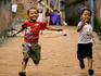 Two boys racing down dirt road.