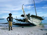Man stands next to traditional trading canoe, Trobriand Islands.