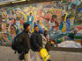 People walk by a mural on 125t Street, Harlem.