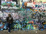 Man standing in front of graffiti, John Lennon Wall.