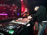 DJ at Mecca nightclub with girl dancing on stage in background.