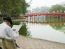 Man reading paper beside The Huc Bridge on Hoan Kiem Lake.