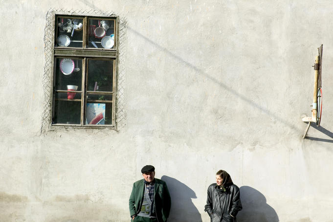 People wait at local bus stop outside hardware shop, Transylvania.