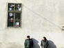 People wait at local bus stop outside hardware shop, Transylvania.