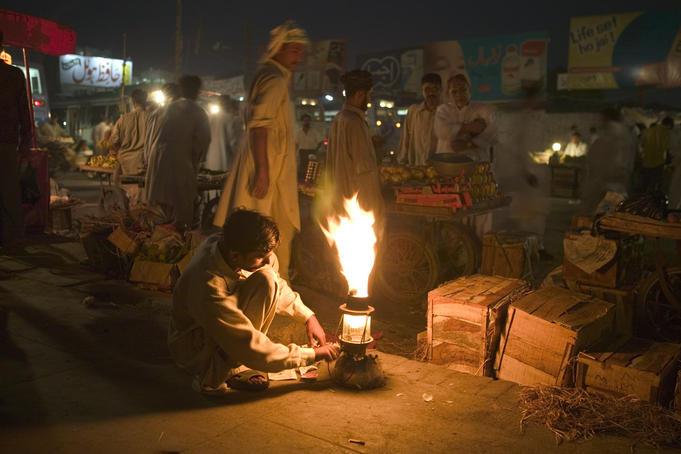 Shop owner gets a lamp burning for the night markets.