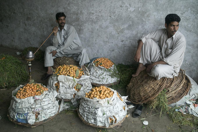 Fruit sellers smoke a pipe in the market.