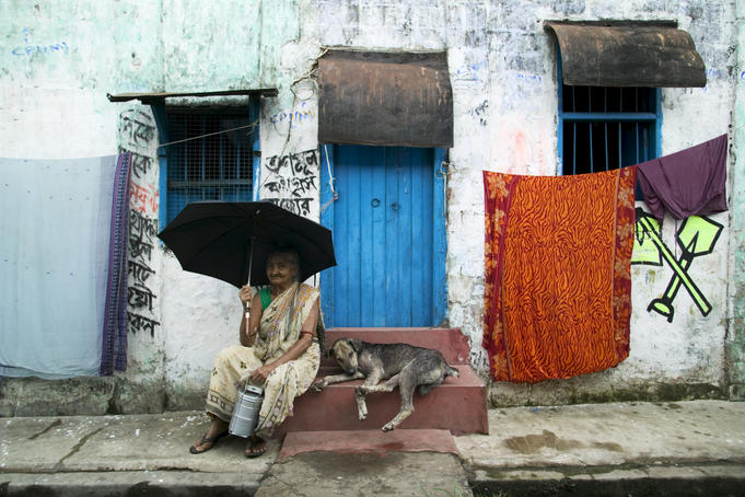 Woman shelters from sun outside her house.