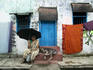 Woman shelters from sun outside her house.