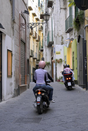 Vespas driving though a laneway.