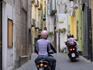Vespas driving though a laneway.
