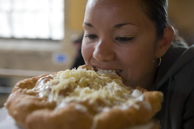 Woman biting into langos bread in Central Market Hall.