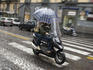 Couple with umbrella on scooter.