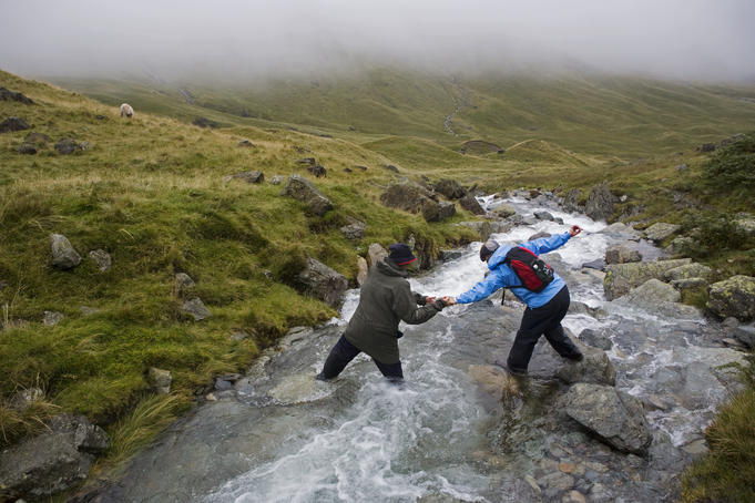Walkers crossing stream on Loft Beck, Lake District.