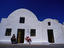 A man sitting outside a whitewashed house typical of the style found on Santorini Island, southern Cyclades Islands.