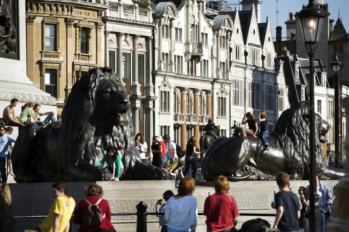 Bronze Lions at Trafalagar Square with Whitehall architecture in background.