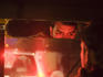 Brake lights reflect off an Auto Rickshaw drivers face.