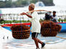 Seaweed farmer carrying two baskets full of seaweed.