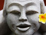 Frangipani flower on a stone carved face.