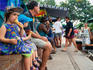 Overview of Parap Outdoor Market: Children sitting on a wall eating ice creams and resting - Darwin, Northern Territory