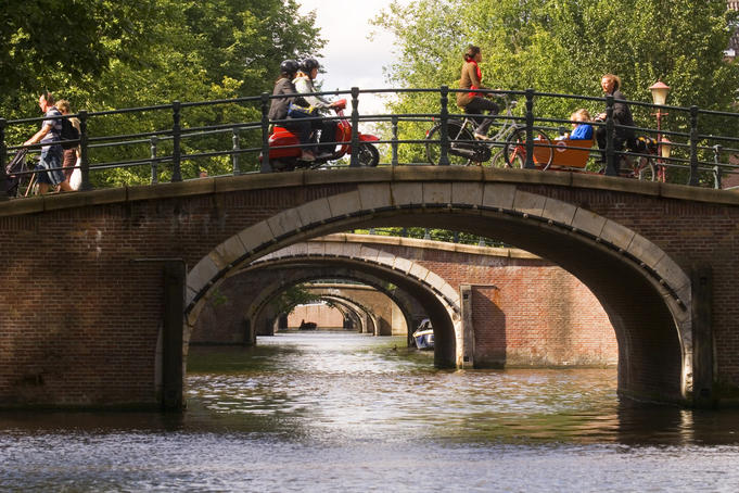 Boats, scooters and pedestrians pass over one of the seven bridges line, the famous 'Golden Bend' in city centre.