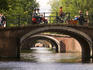 Boats, scooters and pedestrians pass over one of the seven bridges line, the famous 'Golden Bend' in city centre.
