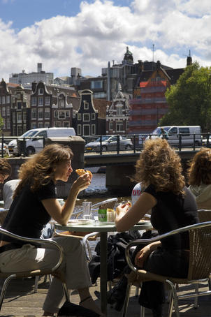 Patrons sit along Kloveniersburgwal canal at Cafe De Jaren in central Amsterdam.
