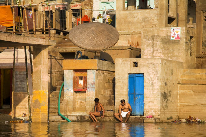 Men contemplate a swim in the river Ganga.