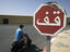 Arabic stop sign and man on vespa outside Medina walls.