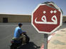Arabic stop sign and man on vespa outside Medina walls.