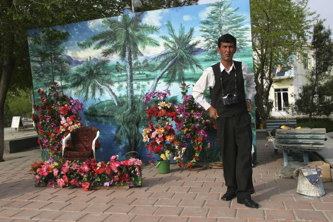 Portrait photographer standing in front of floral backdrop.