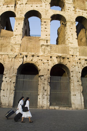 Nuns walking past Colosseum, Roman Forum and Esquiline area.