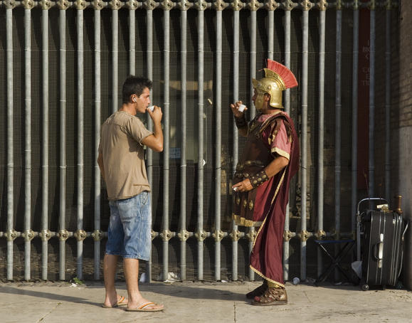 Man in gladiator costume at Colosseum taking a drink break.