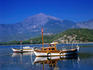 Boats moored on the pristine Mediterranean waters at Phaselis Cove south of Antalya. Mount Olympus is in the background.